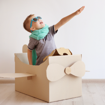 Child prentending to be a pilot while he is playing in a box designed to be a pretend plane